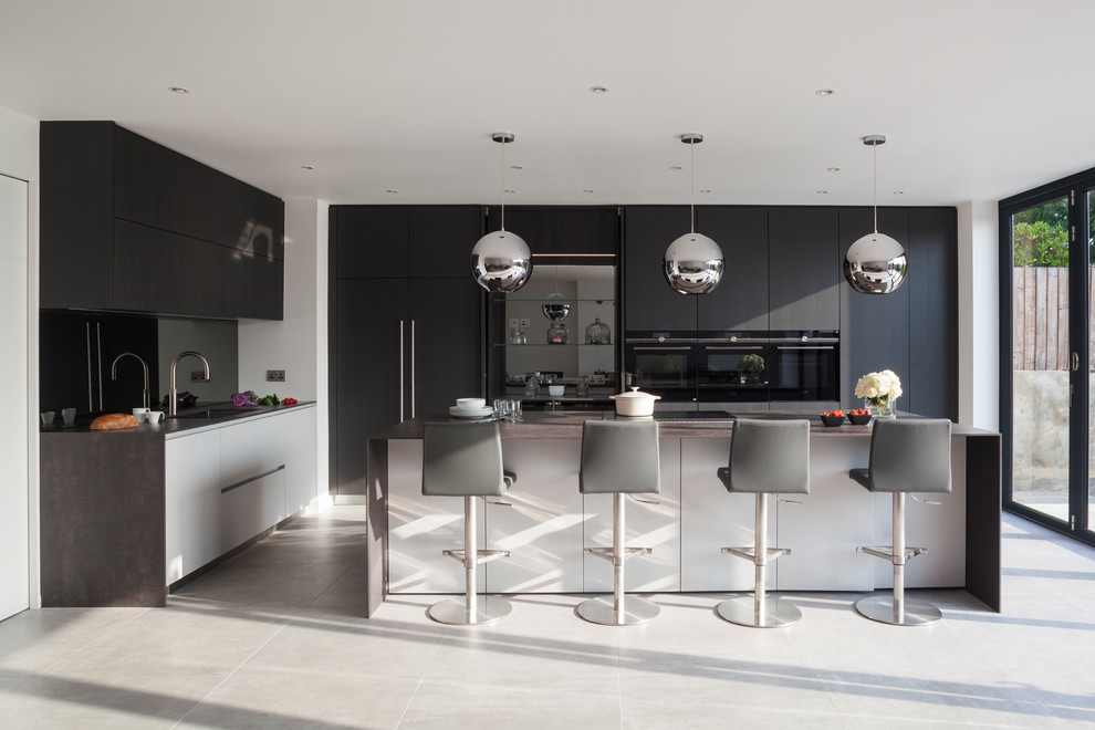 This is an example of an expansive modern l-shaped open plan kitchen in London with flat-panel cabinets, a peninsula, an integrated sink, brown splashback, mirror splashback, stainless steel appliances and brown cabinets.