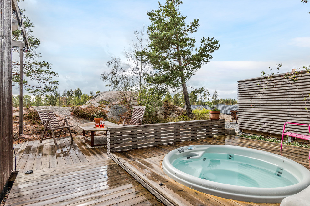 This is an example of a mid-sized scandinavian backyard round aboveground pool in Stockholm with a hot tub and decking.
