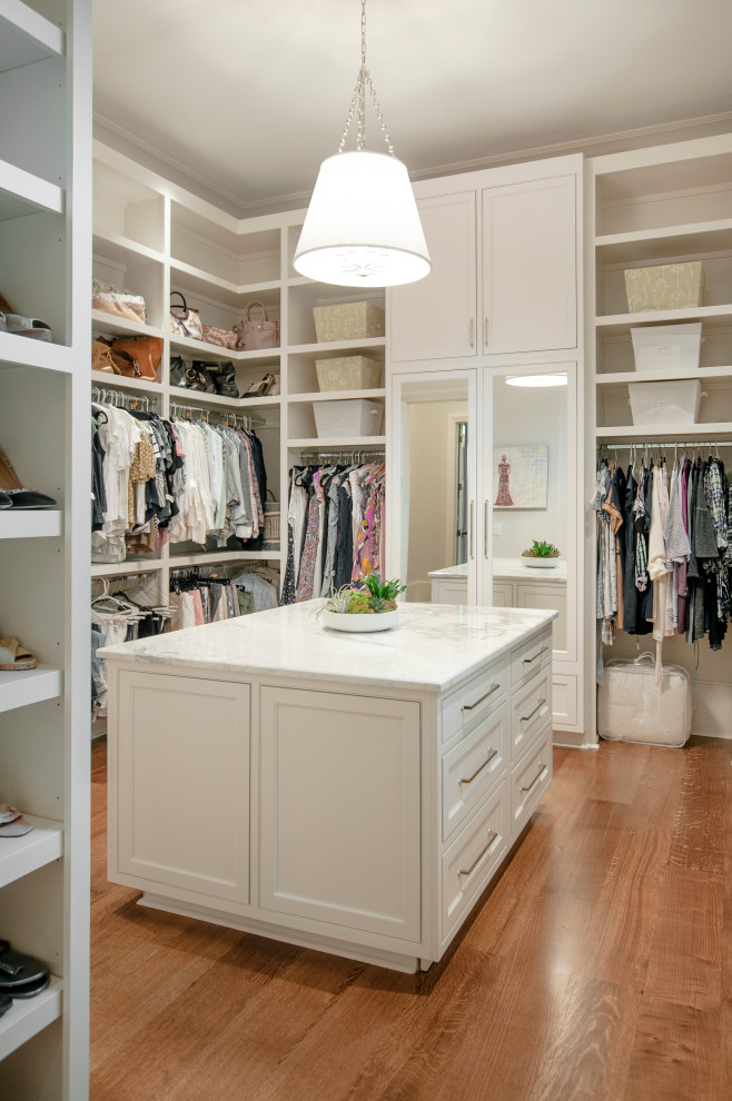 Expansive women's storage and wardrobe in Nashville with beaded inset cabinets, white cabinets, medium hardwood floors and brown floor.
