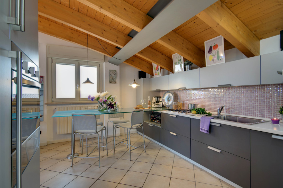 This is an example of a modern galley eat-in kitchen in Other with a drop-in sink, flat-panel cabinets, grey cabinets, pink splashback, mosaic tile splashback, stainless steel appliances, beige floor, white benchtop, exposed beam, vaulted and wood.