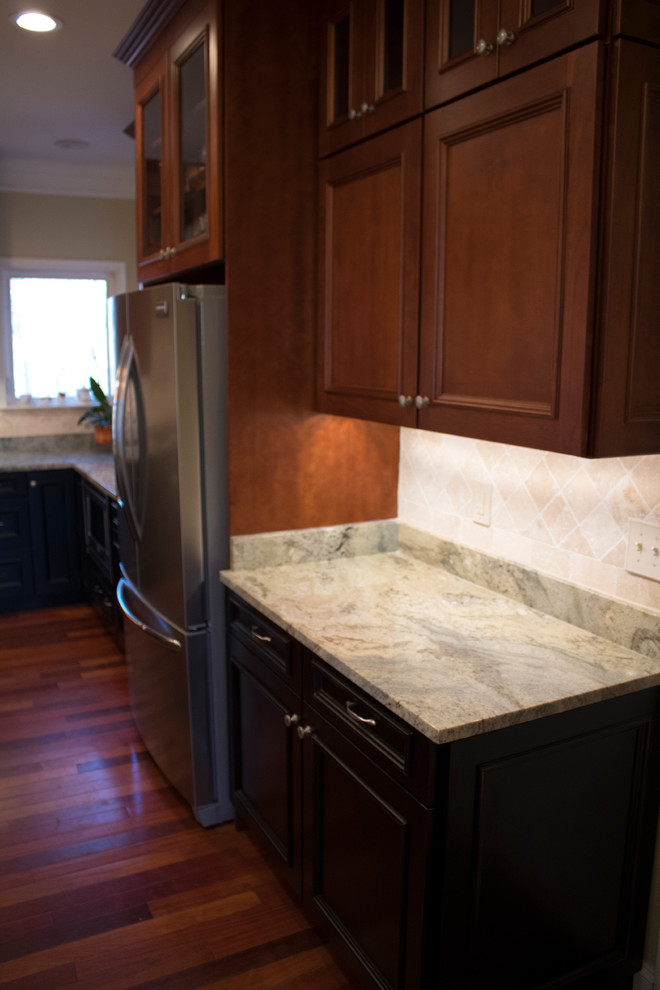 Inspiration for a large transitional l-shaped dark wood floor and brown floor enclosed kitchen remodel in DC Metro with a double-bowl sink, raised-panel cabinets, dark wood cabinets, granite countertops, beige backsplash, limestone backsplash, stainless steel appliances and an island