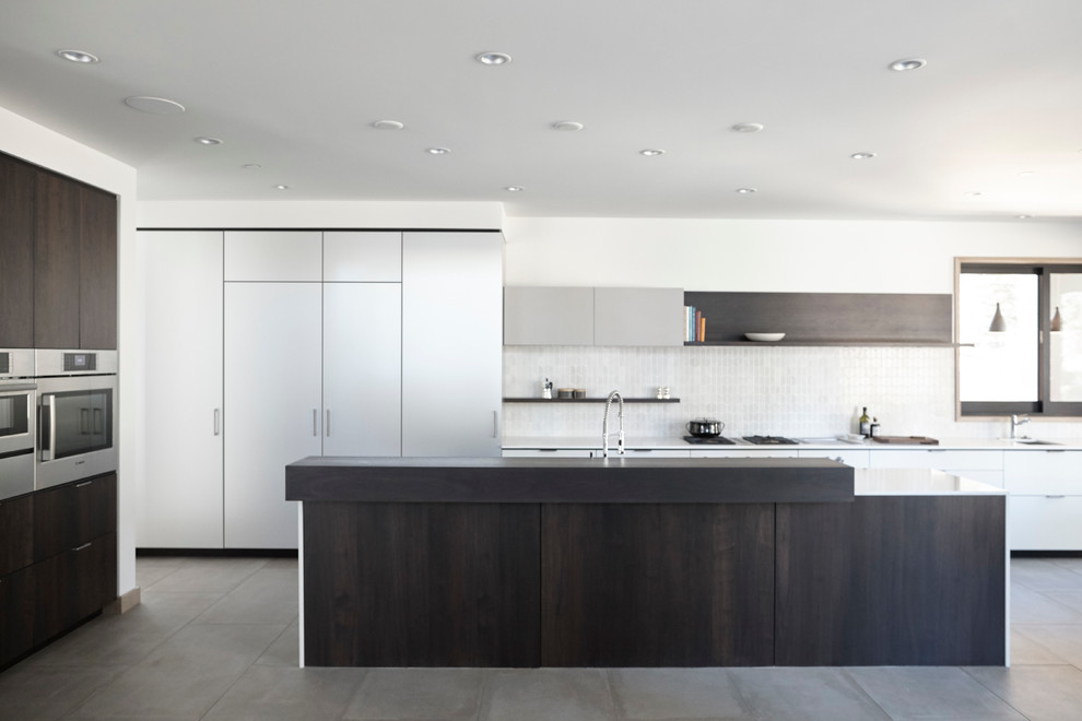 Design ideas for a large modern l-shaped open plan kitchen in San Francisco with an undermount sink, flat-panel cabinets, white cabinets, quartz benchtops, white splashback, ceramic splashback, panelled appliances, porcelain floors and with island.