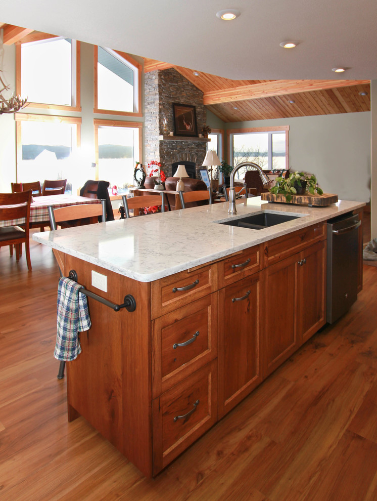 This is an example of a mid-sized arts and crafts l-shaped eat-in kitchen in Other with shaker cabinets, quartz benchtops, stainless steel appliances, vinyl floors, with island, grey benchtop, white cabinets and brown floor.