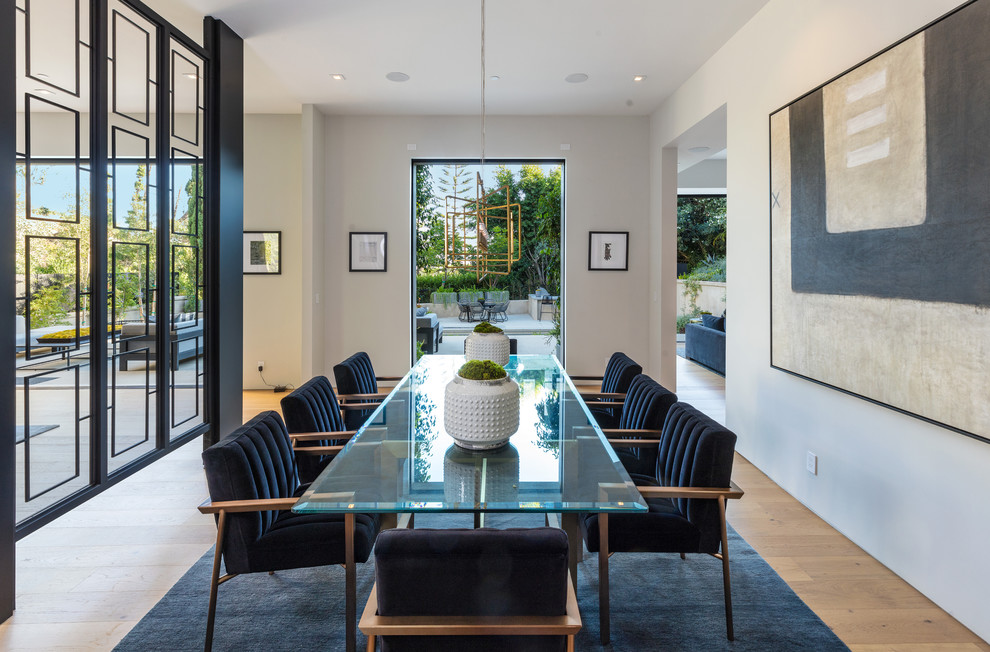 Photo of a contemporary dining room in Los Angeles with white walls, light hardwood floors and beige floor.