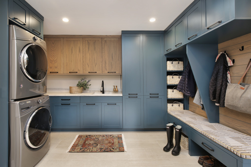 Inspiration for a country u-shaped utility room in Chicago with an undermount sink, shaker cabinets, blue cabinets, a stacked washer and dryer, grey floor and white benchtop.