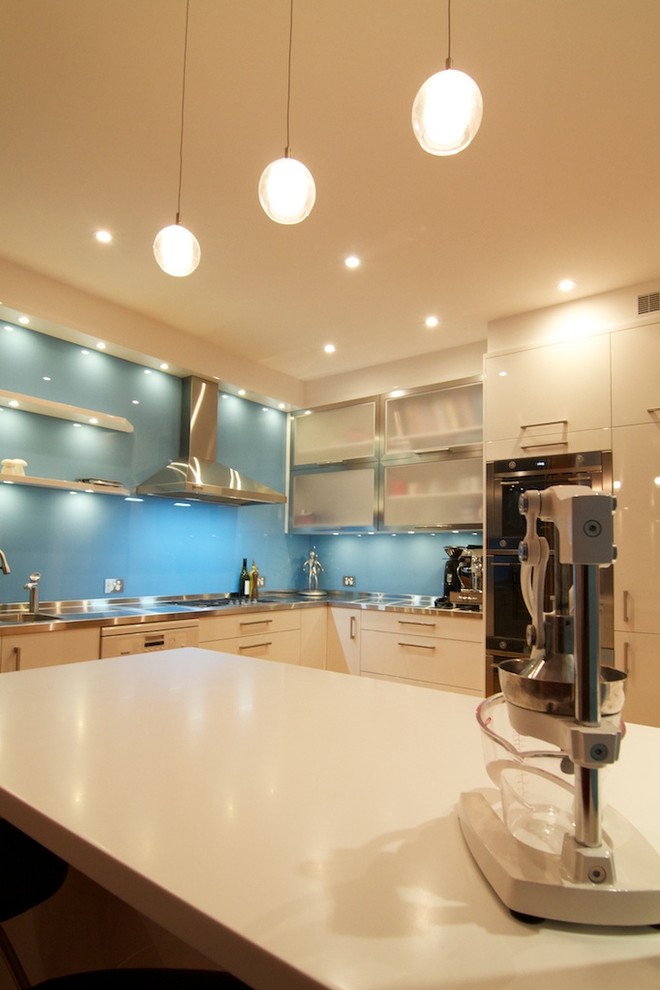 Inspiration for a mid-sized modern l-shaped separate kitchen in Sydney with an integrated sink, flat-panel cabinets, white cabinets, stainless steel benchtops, blue splashback, glass sheet splashback, stainless steel appliances, light hardwood floors, with island and white benchtop.