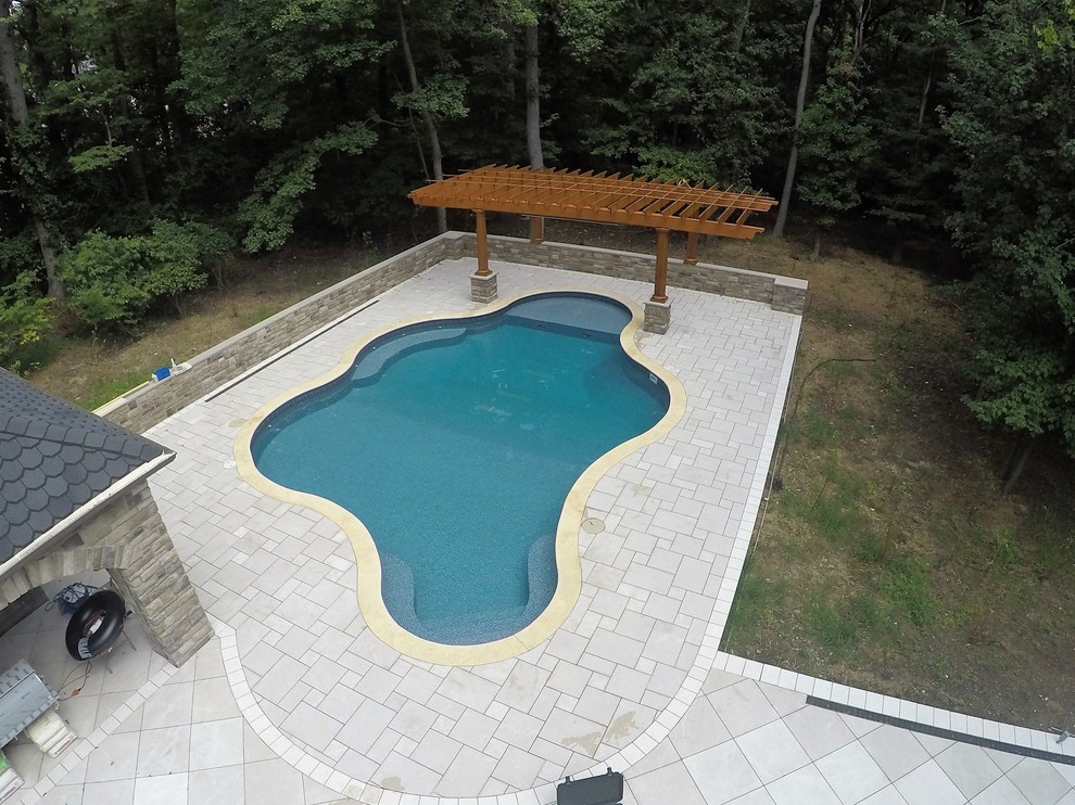 Inspiration for a large contemporary backyard custom-shaped pool in New York with a water feature and concrete pavers.