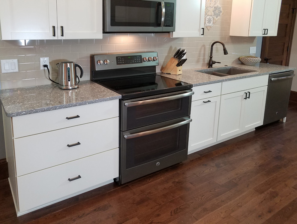 Photo of a mid-sized arts and crafts galley eat-in kitchen in Other with an undermount sink, shaker cabinets, white cabinets, quartz benchtops, beige splashback, ceramic splashback, stainless steel appliances, medium hardwood floors, no island and brown floor.