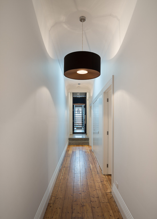 Photo of a mid-sized industrial hallway in Melbourne with white walls and medium hardwood floors.