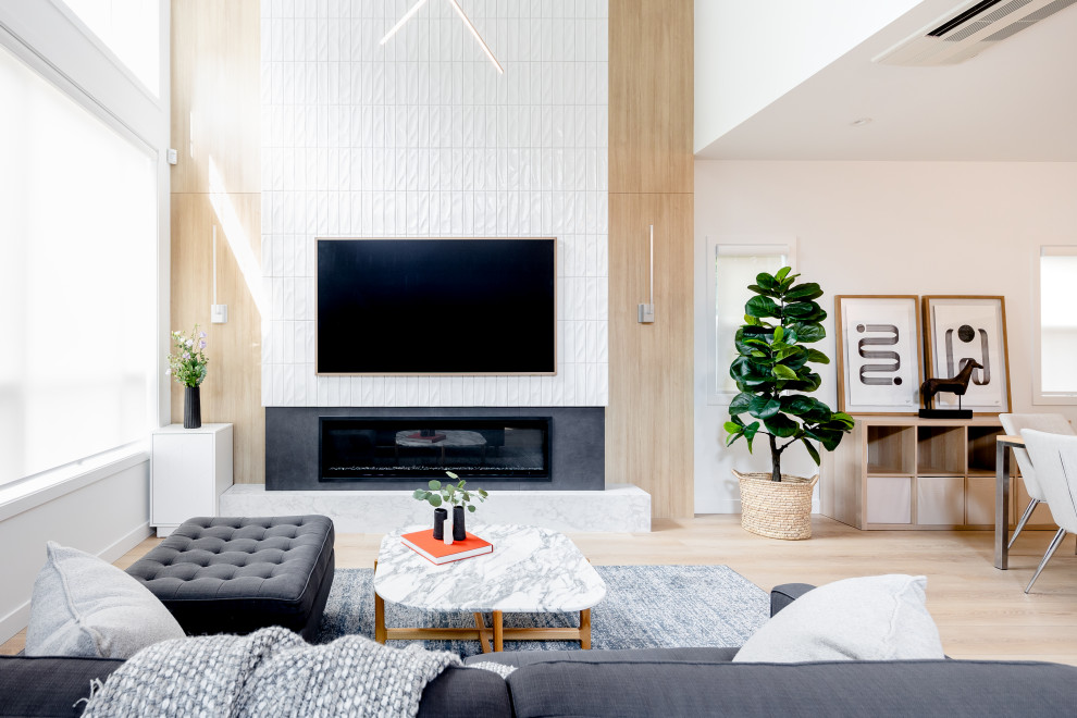 Mittelgroßes, Offenes Modernes Wohnzimmer mit weißer Wandfarbe, hellem Holzboden, Gaskamin, gefliester Kaminumrandung, TV-Wand und beigem Boden in Vancouver