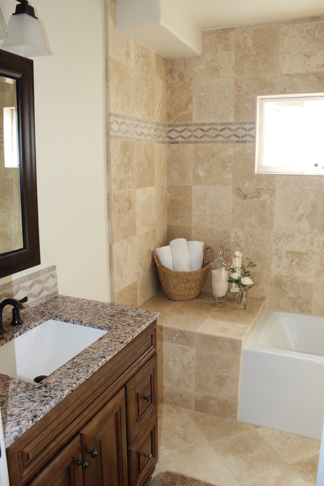 This is an example of a mid-sized mediterranean 3/4 bathroom in Los Angeles with an undermount sink, raised-panel cabinets, medium wood cabinets, granite benchtops, an alcove tub, a shower/bathtub combo, a two-piece toilet, beige tile, stone tile, white walls and travertine floors.