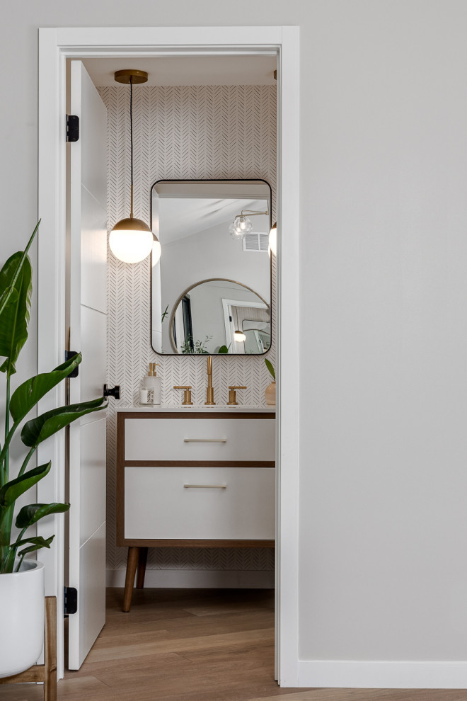 Inspiration for a small 1950s light wood floor, beige floor and wallpaper powder room remodel in Minneapolis with flat-panel cabinets, medium tone wood cabinets, a wall-mount toilet, white walls, an undermount sink, quartz countertops, white countertops and a freestanding vanity