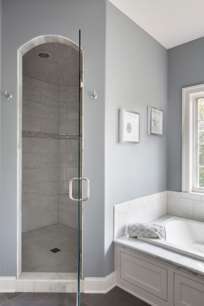 This is an example of a mid-sized arts and crafts master bathroom in Milwaukee with flat-panel cabinets, white cabinets, a drop-in tub, an alcove shower, white tile, grey walls, porcelain floors, an undermount sink, engineered quartz benchtops, grey floor, a hinged shower door, white benchtops and marble.