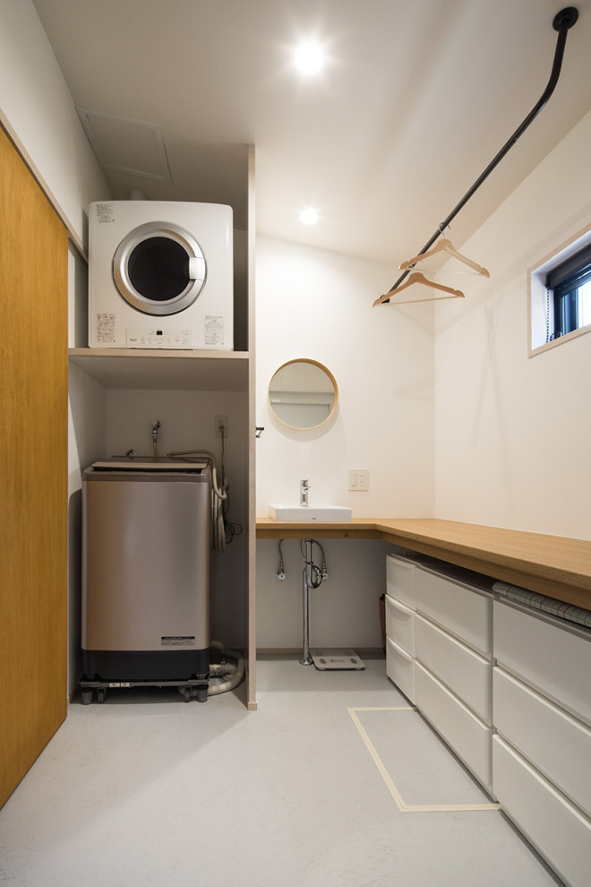 Mid-century modern linoleum floor and gray floor laundry room photo in Other with white walls, a stacked washer/dryer and beige countertops