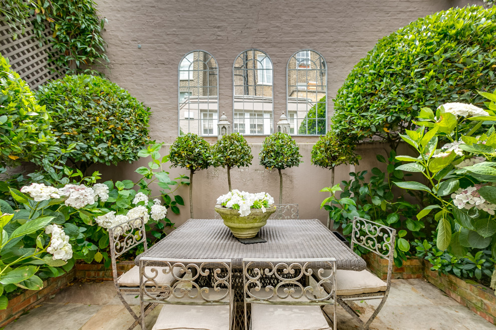 Photo of a romantic courtyard garden in London with a raised bed and natural stone paving.