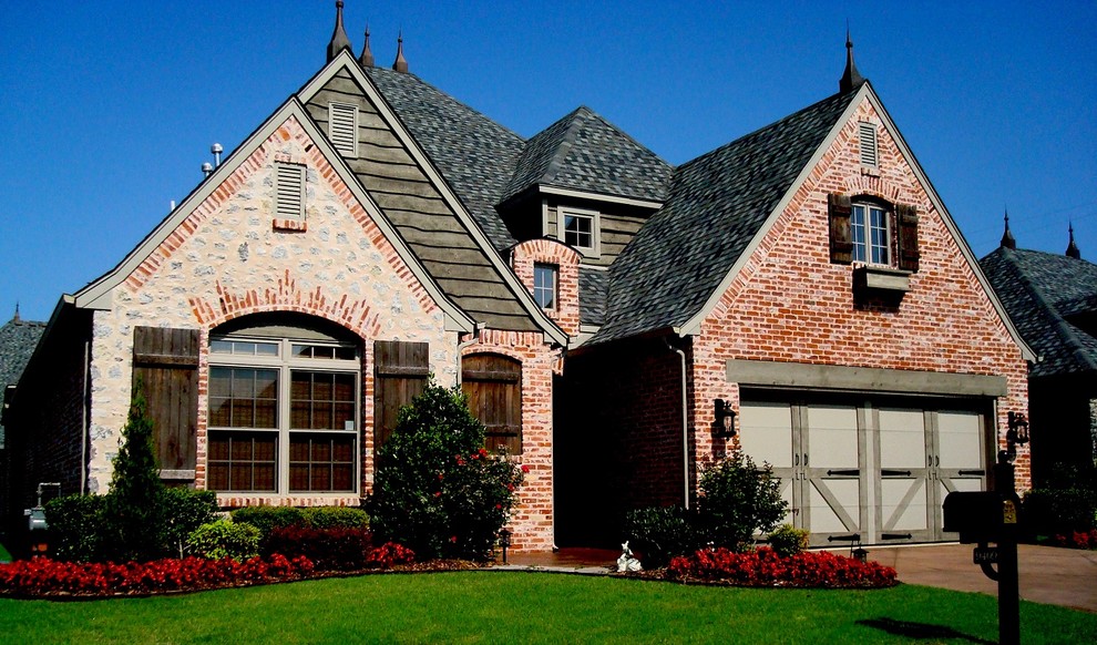 Photo of a mid-sized transitional two-storey brick red house exterior in Other with a gable roof and a shingle roof.