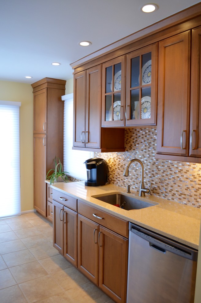 Inspiration for a mid-sized transitional galley porcelain tile eat-in kitchen remodel in New York with an undermount sink, recessed-panel cabinets, medium tone wood cabinets, quartz countertops, beige backsplash, mosaic tile backsplash, stainless steel appliances and no island
