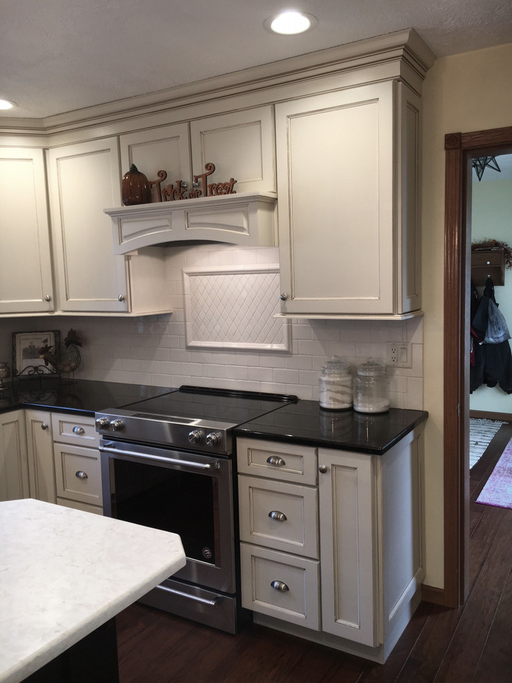 Eat-in kitchen - large transitional medium tone wood floor and brown floor eat-in kitchen idea with an undermount sink, flat-panel cabinets, white cabinets, granite countertops, white backsplash, porcelain backsplash, stainless steel appliances and an island