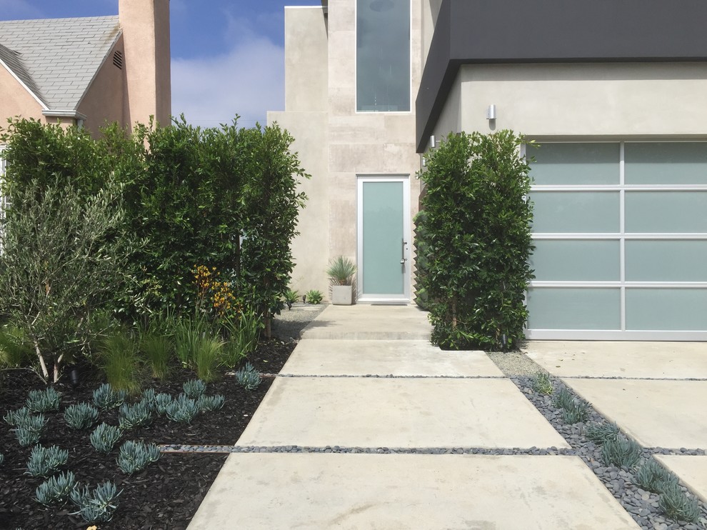 This is an example of a contemporary front yard driveway in Los Angeles with concrete pavers.