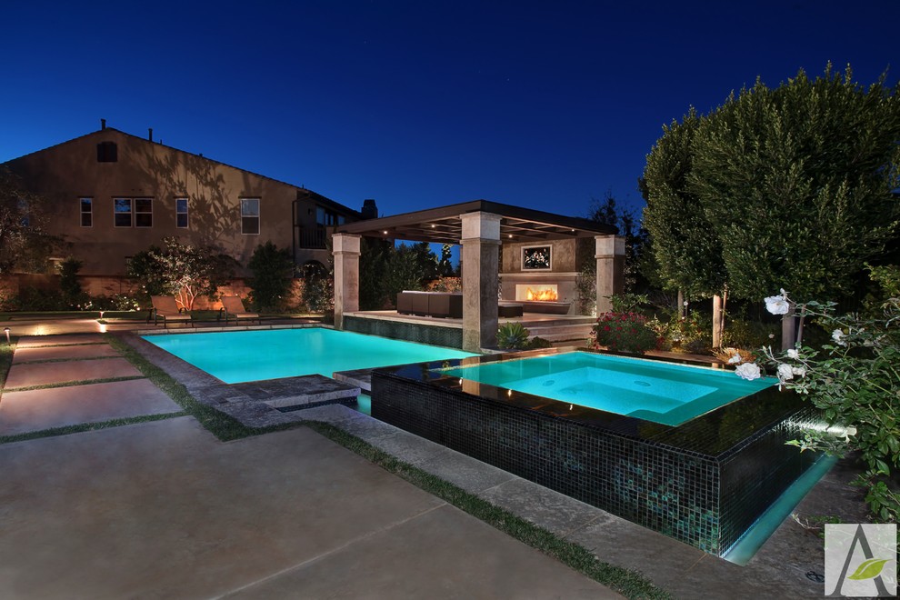 Large mediterranean backyard rectangular natural pool in Orange County with a hot tub and natural stone pavers.