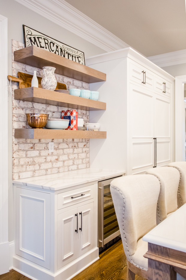 Inspiration for a large transitional u-shaped medium tone wood floor and brown floor eat-in kitchen remodel in Atlanta with a farmhouse sink, raised-panel cabinets, white cabinets, quartz countertops, white backsplash, brick backsplash, stainless steel appliances, an island and white countertops