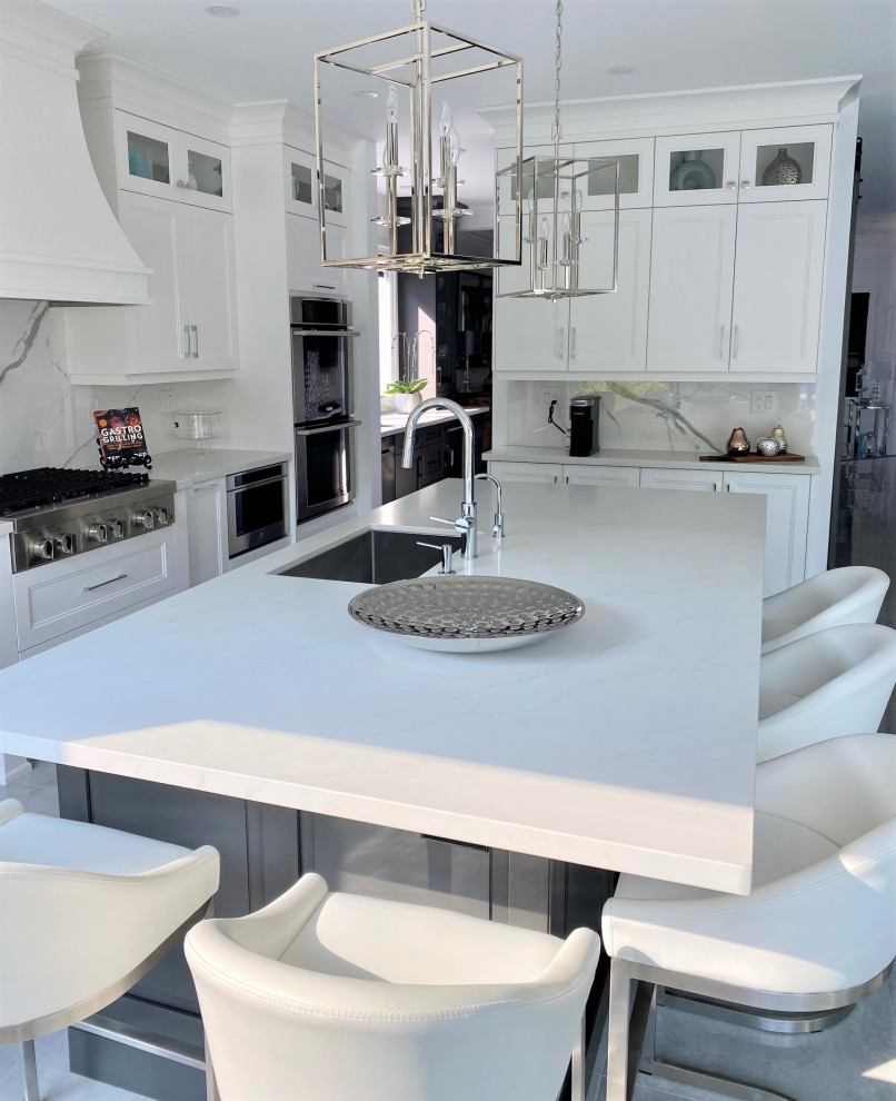 Open concept kitchen - large transitional l-shaped porcelain tile and white floor open concept kitchen idea in Toronto with an undermount sink, recessed-panel cabinets, white cabinets, quartz countertops, white backsplash, stone slab backsplash, stainless steel appliances, an island and white countertops