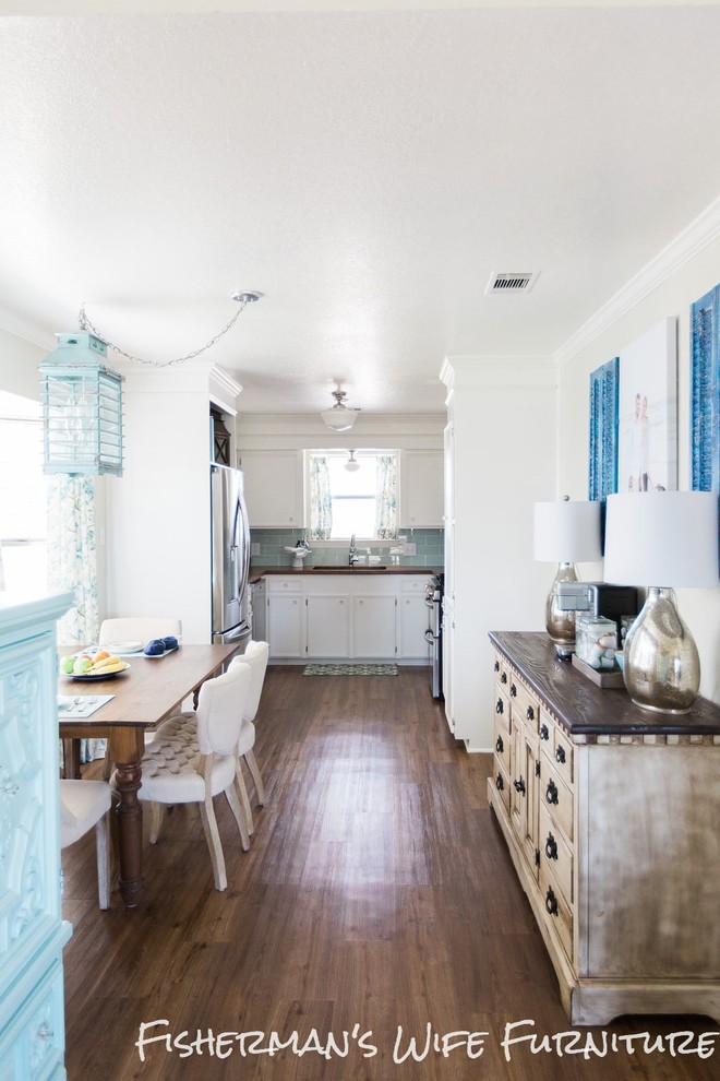 Photo of a mid-sized beach style eat-in kitchen in Houston with a single-bowl sink, flat-panel cabinets, white cabinets, wood benchtops, blue splashback, ceramic splashback, stainless steel appliances, vinyl floors and no island.