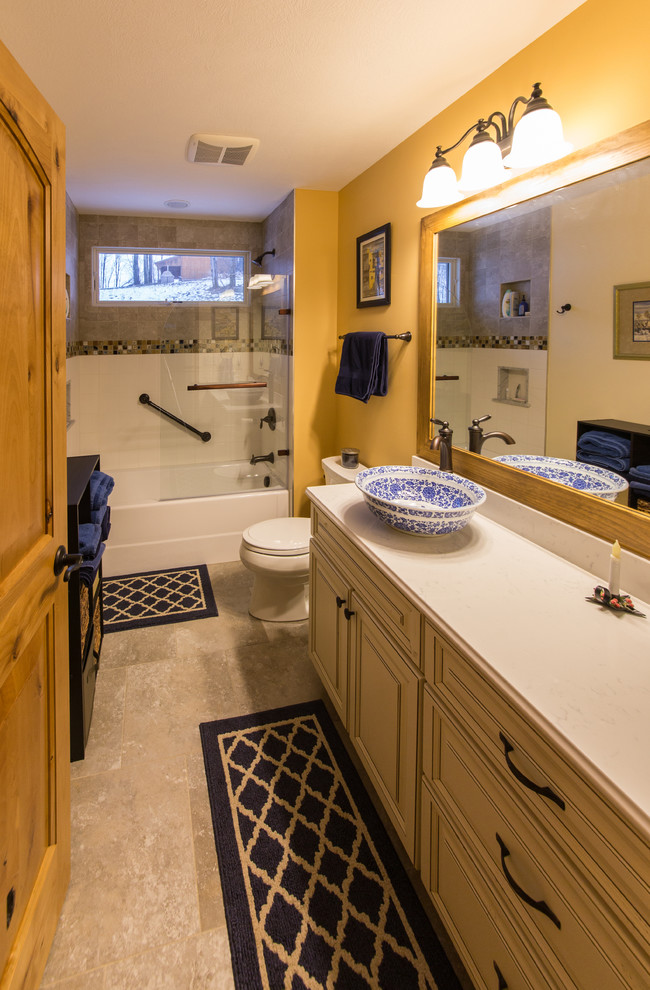 Alcove bathtub - mid-sized rustic 3/4 limestone floor and beige floor alcove bathtub idea with raised-panel cabinets, beige cabinets, a two-piece toilet, yellow walls, a vessel sink and marble countertops