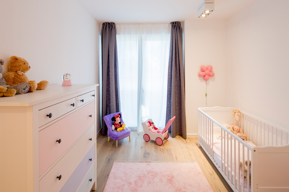 Babyzimmer With Schlafplatz, weißer Wandfarbe, braunem Holzboden and beigem Boden in Dusseldorf