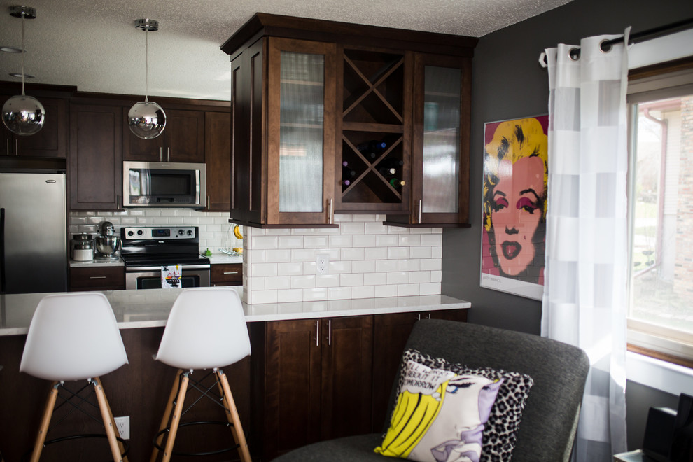 Enclosed kitchen - mid-sized transitional u-shaped enclosed kitchen idea in Omaha with shaker cabinets, dark wood cabinets, quartz countertops, white backsplash, subway tile backsplash, stainless steel appliances and a peninsula