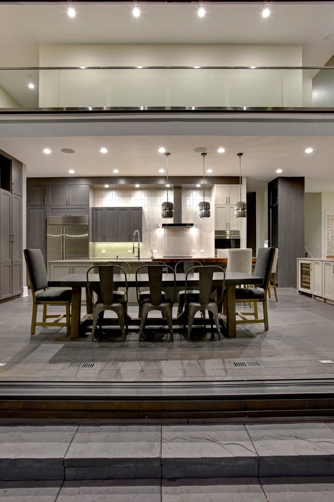 Large transitional u-shaped medium tone wood floor and gray floor eat-in kitchen photo in Chicago with a double-bowl sink, recessed-panel cabinets, light wood cabinets, quartzite countertops, beige backsplash, glass tile backsplash, stainless steel appliances and two islands