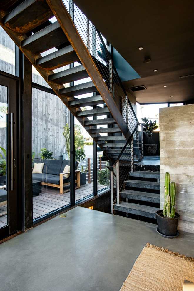 This is an example of a mid-sized industrial concrete floating staircase in Los Angeles with metal railing, brick walls and metal risers.