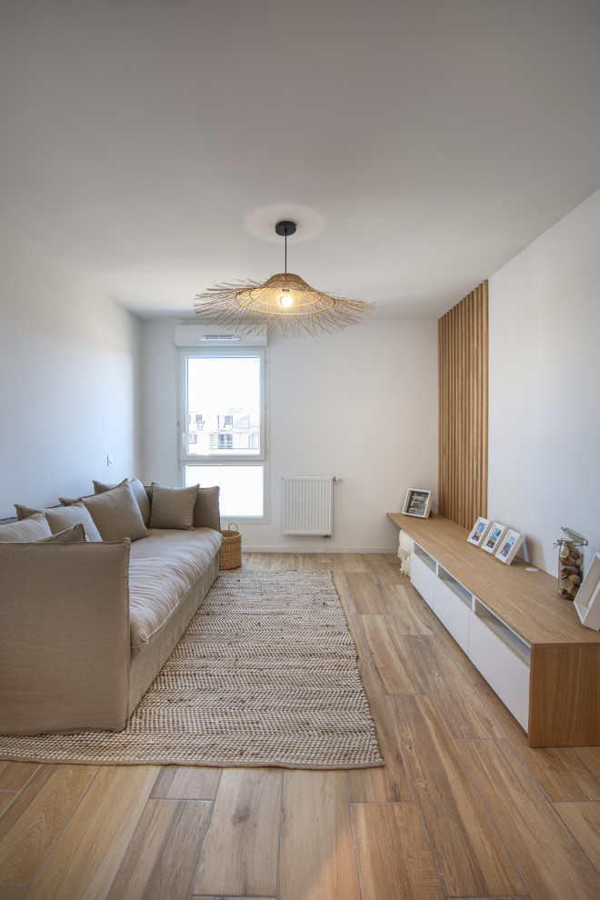 Foto de salón cerrado costero pequeño sin chimenea y televisor con paredes blancas, madera, suelo de madera clara y suelo marrón