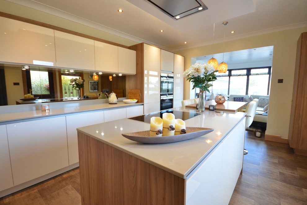 This is an example of a mid-sized contemporary u-shaped eat-in kitchen in Glasgow with laminate benchtops, mirror splashback, with island, a double-bowl sink, flat-panel cabinets, white cabinets, white splashback, white appliances, medium hardwood floors and brown floor.