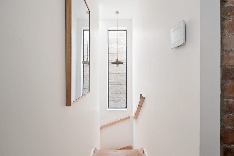 Ejemplo de escalera en L actual pequeña con escalones de madera, contrahuellas de madera, barandilla de madera y ladrillo