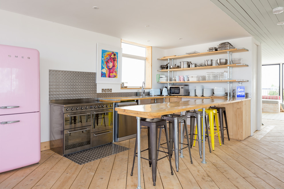 Design ideas for a large industrial u-shaped kitchen in Dorset with a drop-in sink, open cabinets, light wood cabinets, wood benchtops, metallic splashback, metal splashback, stainless steel appliances, light hardwood floors, a peninsula and beige floor.