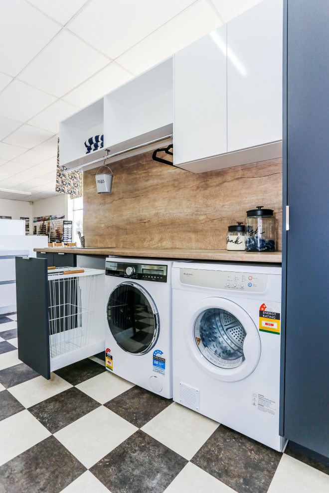 Design ideas for a small contemporary single-wall dedicated laundry room in Other with a drop-in sink, flat-panel cabinets, grey cabinets, laminate benchtops, brown walls, vinyl floors, a side-by-side washer and dryer and brown benchtop.