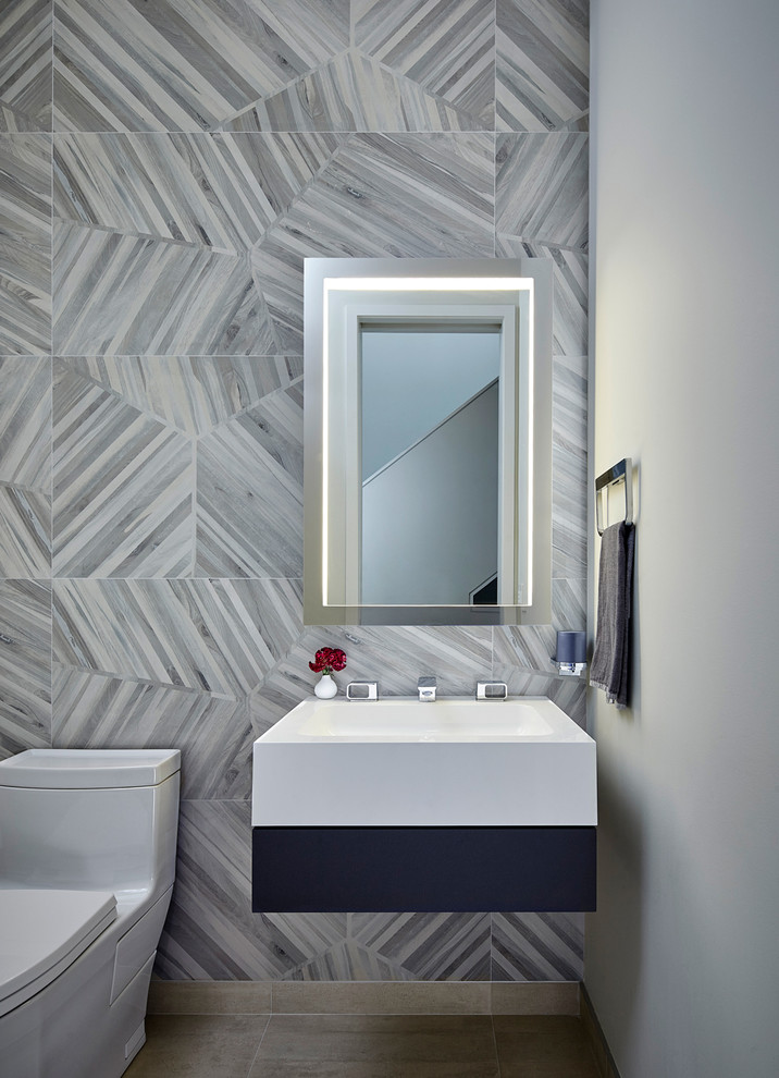 This is an example of a large contemporary powder room in Chicago with a one-piece toilet, gray tile, grey walls and a wall-mount sink.