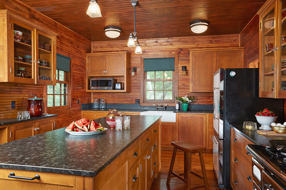 Design ideas for a mid-sized country separate kitchen in Minneapolis with a farmhouse sink, glass-front cabinets, medium wood cabinets, timber splashback, medium hardwood floors, with island, quartz benchtops, brown splashback, stainless steel appliances and brown floor.