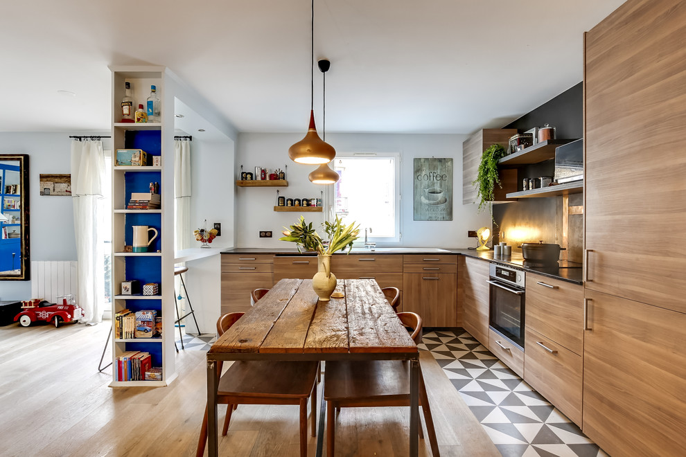 This is an example of an eclectic l-shaped eat-in kitchen in Paris with an undermount sink, flat-panel cabinets, medium wood cabinets, black splashback, panelled appliances and no island.