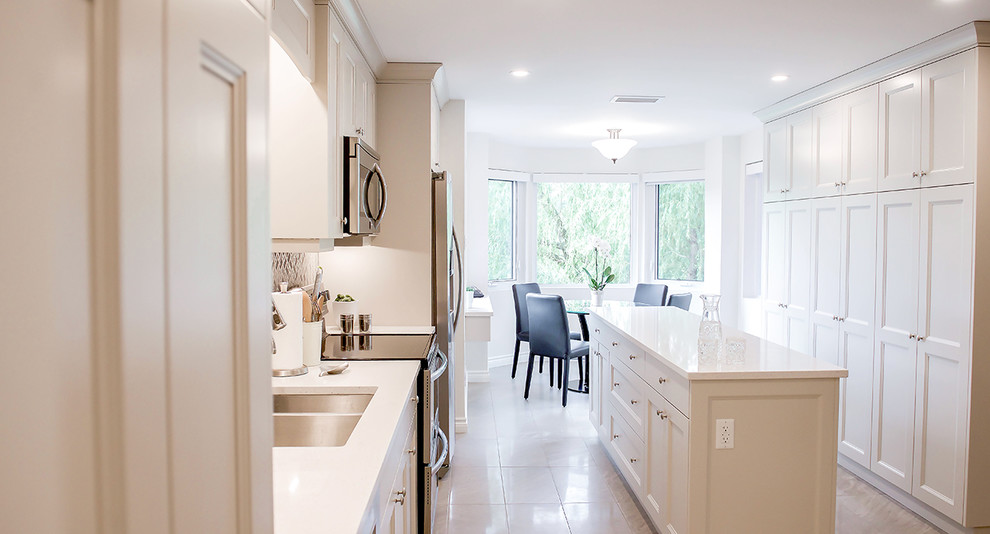 Inspiration for a mid-sized transitional galley porcelain tile and gray floor kitchen pantry remodel in Toronto with an undermount sink, shaker cabinets, gray cabinets, quartz countertops, metallic backsplash, stainless steel appliances, an island and white countertops