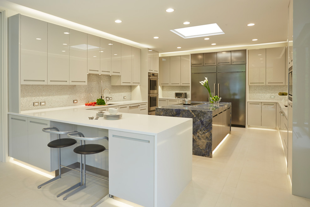 This is an example of a large contemporary u-shaped kitchen in Chicago with flat-panel cabinets, white cabinets, stainless steel appliances, with island, beige floor, an undermount sink, solid surface benchtops, grey splashback, mosaic tile splashback and porcelain floors.