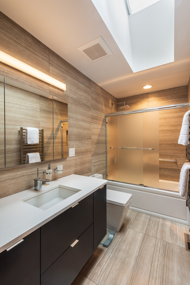 Photo of a contemporary 3/4 bathroom in Other with blue cabinets, an alcove tub, a shower/bathtub combo, brown tile, light hardwood floors, an undermount sink, brown floor, a sliding shower screen and white benchtops.