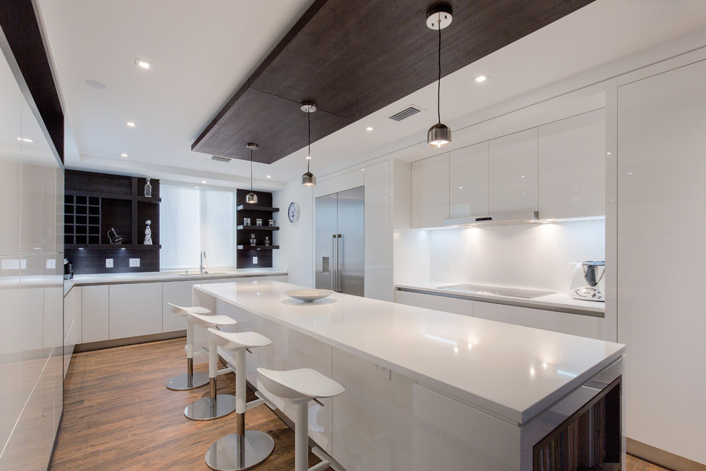 Inspiration for a contemporary galley kitchen in Miami with an undermount sink, flat-panel cabinets, white cabinets, white splashback, stainless steel appliances, medium hardwood floors and with island.