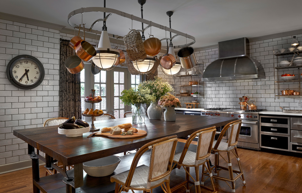 Design ideas for a mid-sized industrial single-wall eat-in kitchen in Chicago with flat-panel cabinets, black cabinets, white splashback, subway tile splashback, stainless steel appliances, medium hardwood floors, with island, quartz benchtops and brown floor.