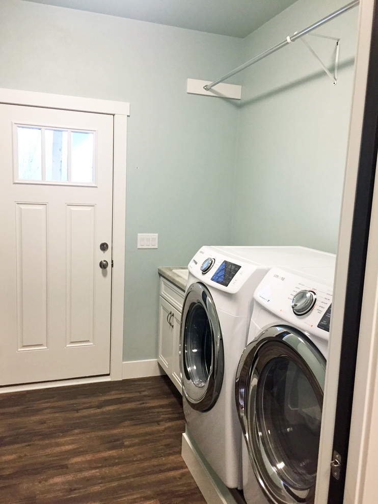 This is an example of a mid-sized arts and crafts single-wall dedicated laundry room in Other with a drop-in sink, recessed-panel cabinets, white cabinets, green walls, dark hardwood floors and a side-by-side washer and dryer.