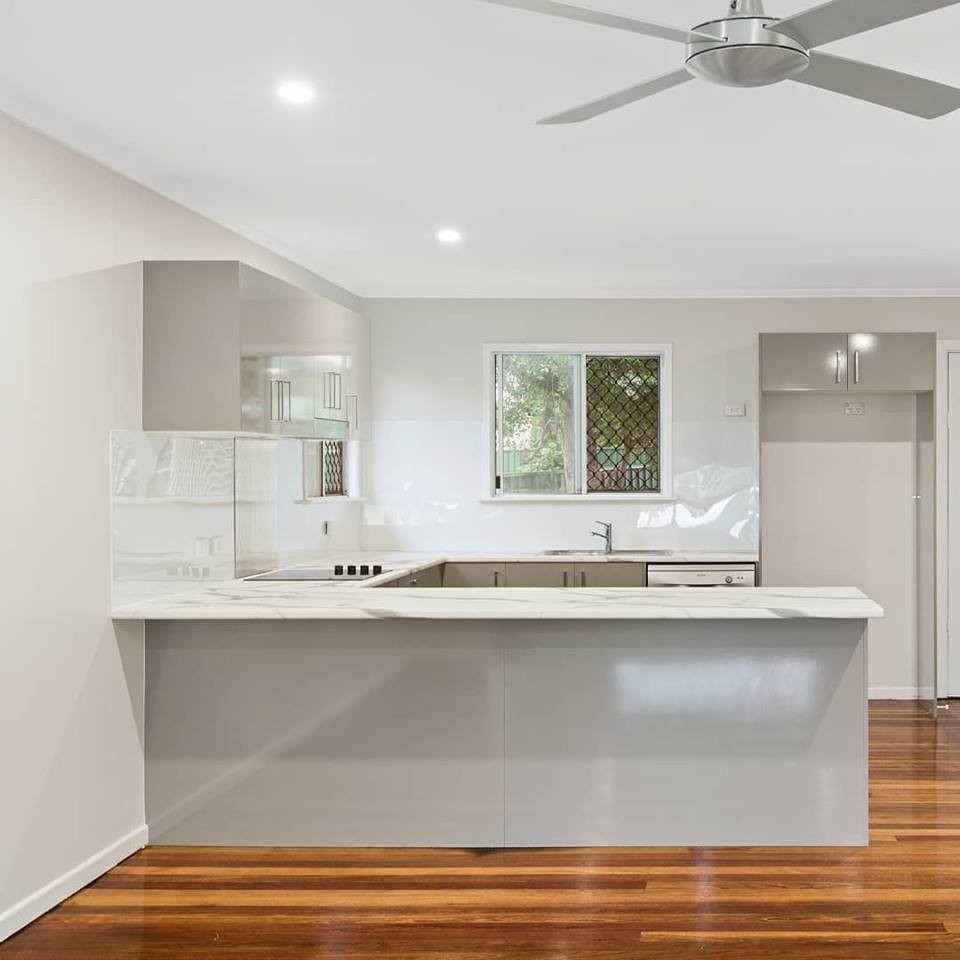 Design ideas for a transitional u-shaped kitchen in Brisbane with an integrated sink, white splashback and white benchtop.