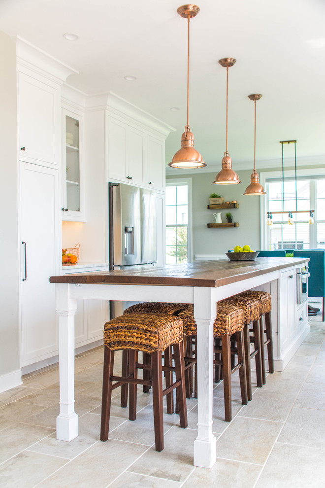 Mid-sized country galley eat-in kitchen in DC Metro with a farmhouse sink, flat-panel cabinets, white cabinets, wood benchtops, white splashback, stainless steel appliances, porcelain floors, with island, beige floor and brown benchtop.
