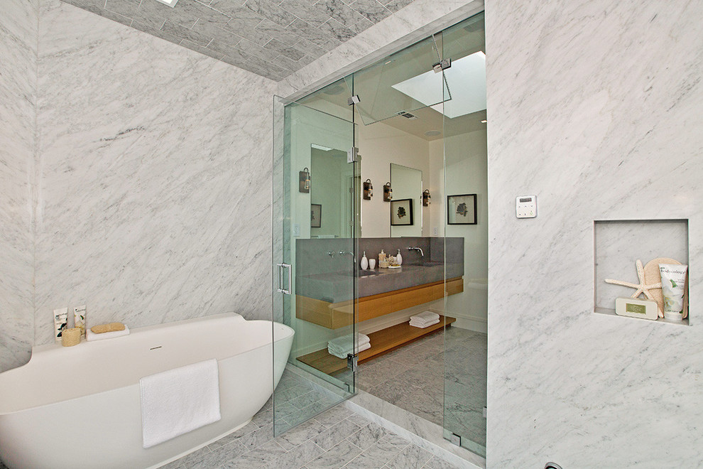 Photo of a large contemporary master bathroom in San Francisco with furniture-like cabinets, medium wood cabinets, an alcove tub, an open shower, a wall-mount toilet, white tile, stone slab, beige walls, marble floors, an undermount sink and concrete benchtops.