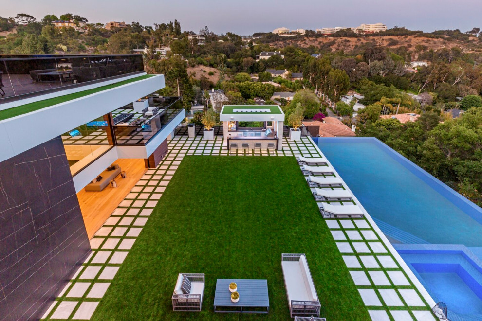 Modelo de piscina infinita moderna grande rectangular en patio trasero con paisajismo de piscina